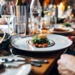 Elegant dining table setup with gourmet dish and wine glasses.