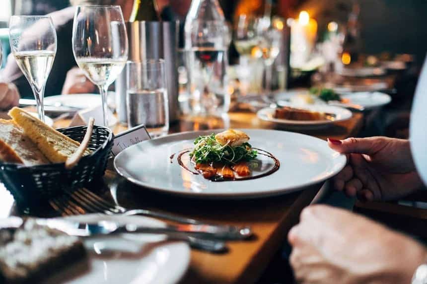 Elegant dining table setup with gourmet dish and wine glasses.