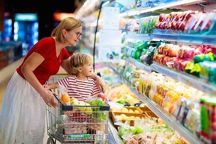 Mother and child selecting fruits while grocery shopping together.