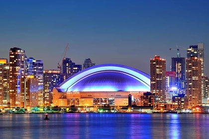 Rogers Centre lit up at night with Toronto skyline in the background.