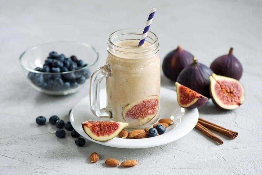 Fig and blueberry smoothie in a mason jar with fresh ingredients.