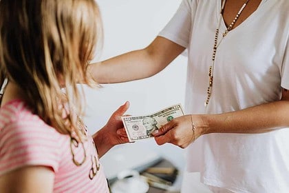 Adult giving cash to child, concept of financial support.