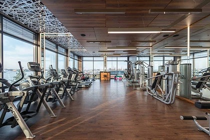 Modern gym with cardio machines and wooden floors.