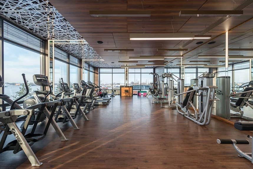 Modern gym with cardio machines and wooden floors.