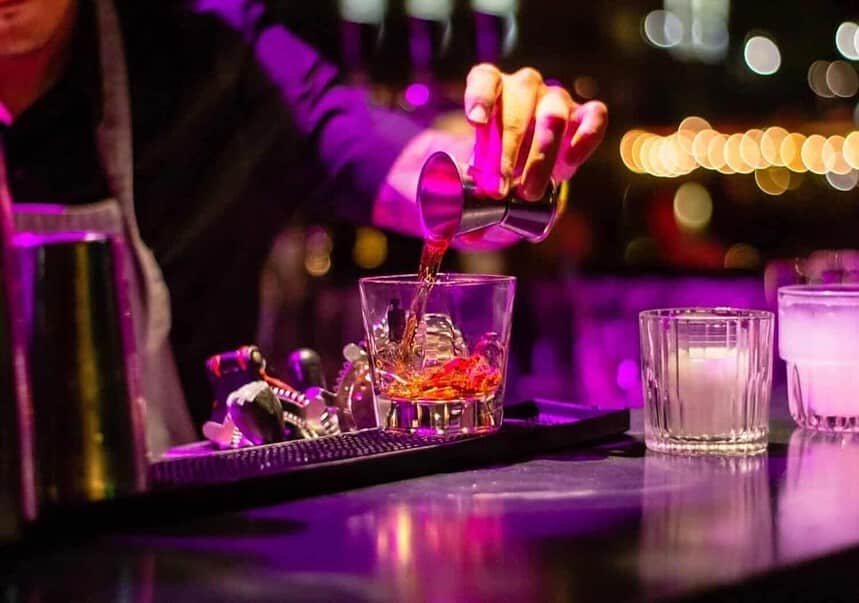 Bartender pouring cocktail at vibrant nightlife venue.