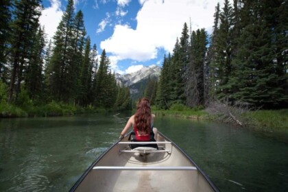 Woman canoeing in serene lake with mountain view.
