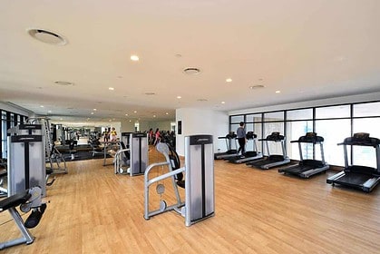 Spacious modern gym with equipment and large windows.