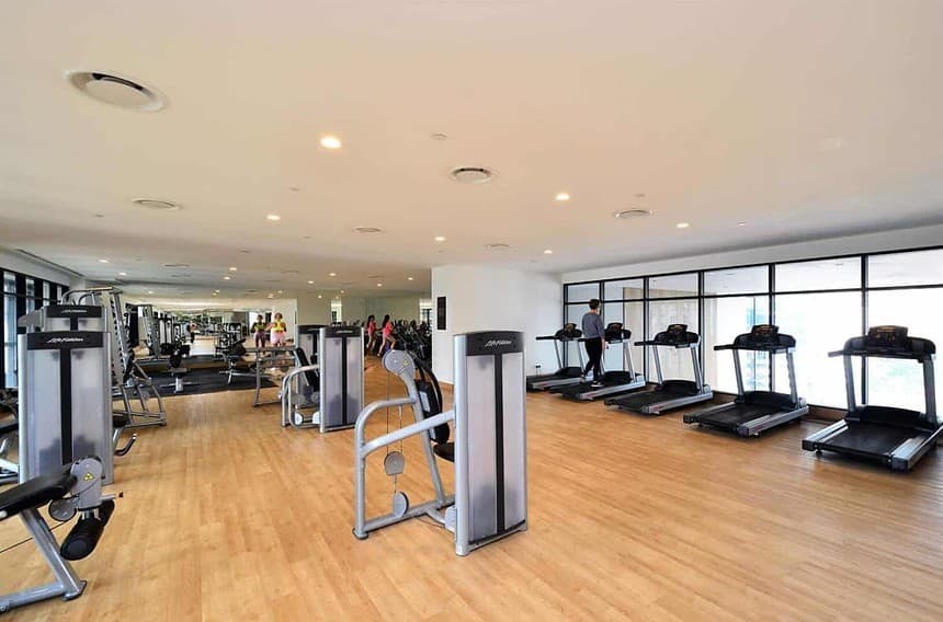 Spacious modern gym with equipment and large windows.