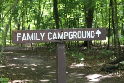 Family campground sign in a forest setting.