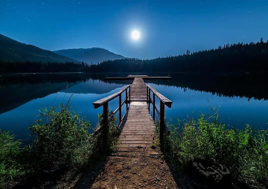 Serene lakeside pier under moonlight in British Columbia.