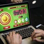 Person playing online roulette casino game on laptop.