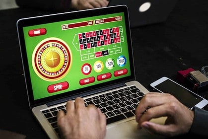 Person playing online roulette casino game on laptop.