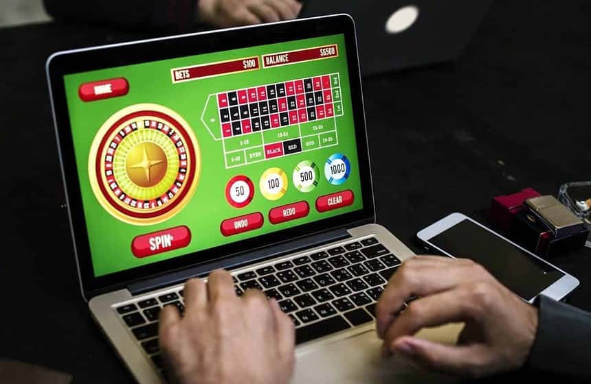 Person playing online roulette casino game on laptop.