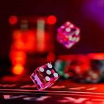 Craps dice rolling on casino table with bokeh lights.