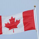 Canadian flag waving against clear sky.