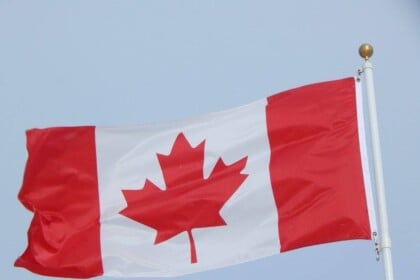Canadian flag waving against clear sky.
