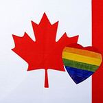 Canadian flag with a rainbow-colored heart overlay.
