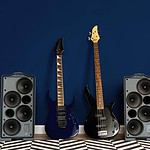Electric guitars and speakers against a navy blue wall.