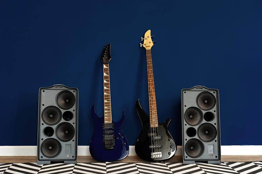 Electric guitars and speakers against a navy blue wall.