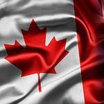 Canadian and New Zealand flags intertwined in union.