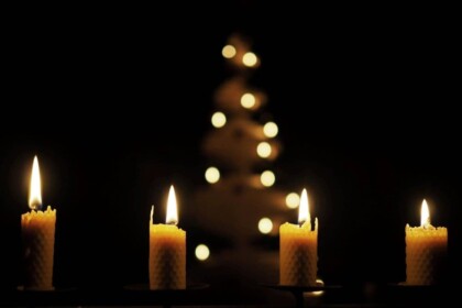 Candles with Christmas tree bokeh lights in background.
