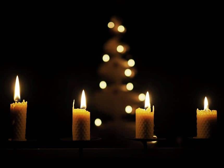 Candles with Christmas tree bokeh lights in background.