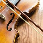 Classic violin with bow on wooden background