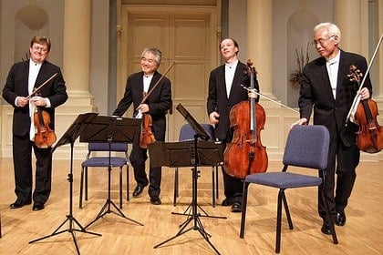 Classical string quartet musicians on stage with instruments.