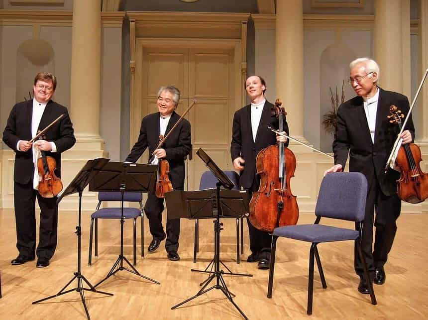 Classical string quartet musicians on stage with instruments.