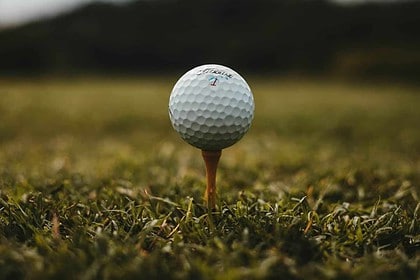 Close-up of golf ball on tee at dusk.