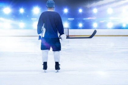 Ice hockey player ready for game under arena spotlights.