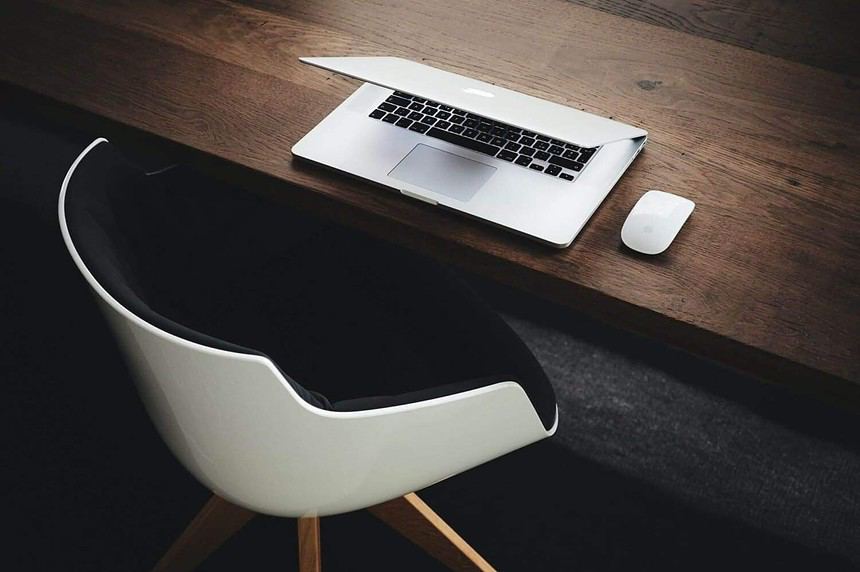 Minimalist office desk with laptop and chair.