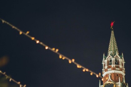 Illuminated carousel at night with festive lights and historic tower backdrop.