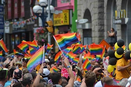 Colorful LGBTQ+ pride parade with rainbow flags and cheerful crowd.