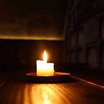 Single candle burning in dark room.