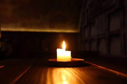 Single candle burning in dark room.