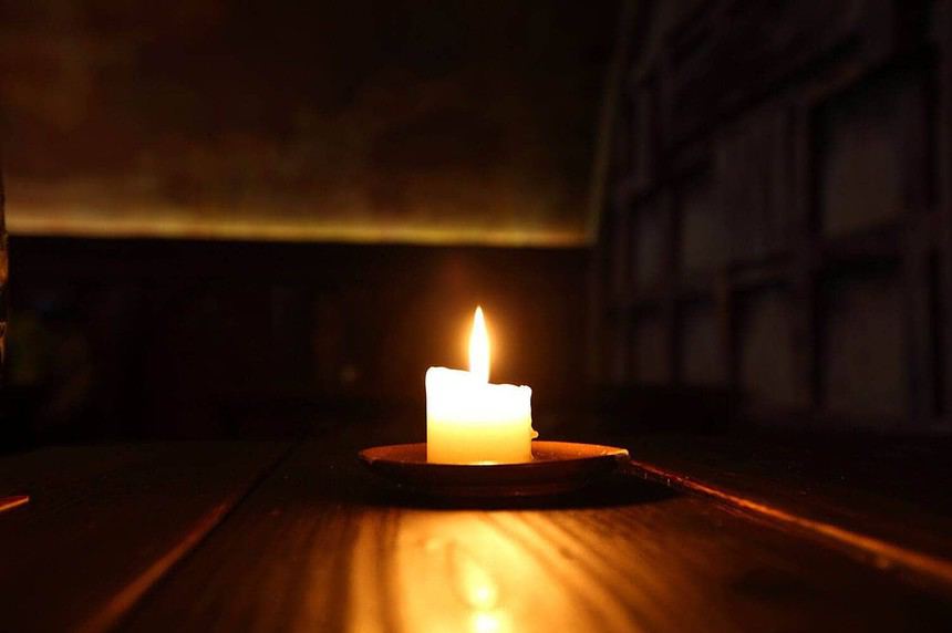 Single candle burning in dark room.