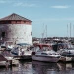 Marina with boats and historical tower under clear skies.