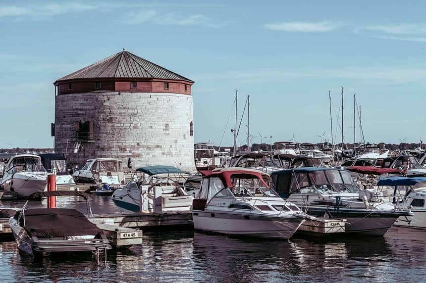 Marina with boats and historical tower under clear skies.