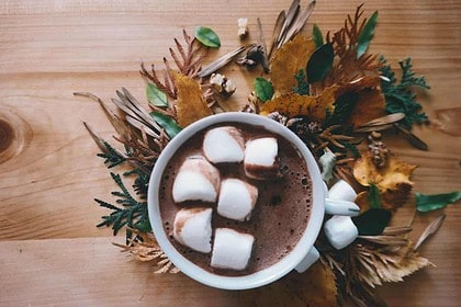 Cozy autumn hot chocolate with marshmallows and fall leaves.