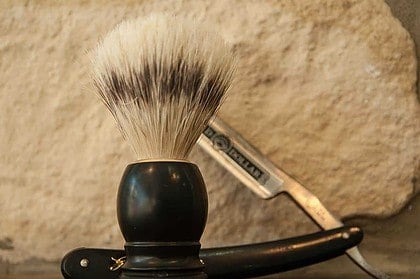 Vintage shaving brush and straight razor on a rustic background.