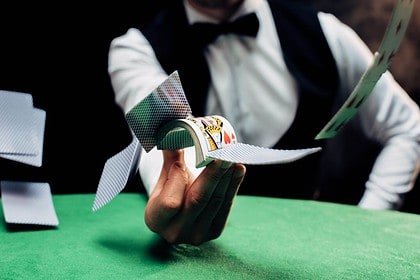 Blackjack dealer distributing cards on casino table.
