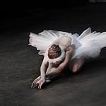 Elegant ballerina in a dynamic pose on a dark stage.