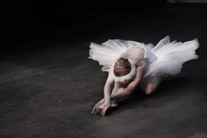Elegant ballerina in a dynamic pose on a dark stage.