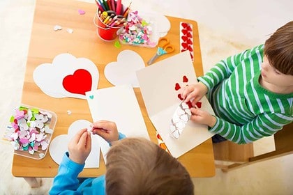 Children making Valentines Day crafts with paper hearts.