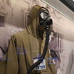 Historical police uniform and gas mask on display at a museum.
