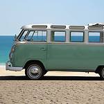 Vintage minivan parked on beach with ocean backdrop.