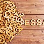 Wooden letters spelling ESSAY on a wooden background.