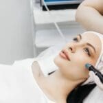 Woman receiving hydrafacial treatment at beauty clinic.