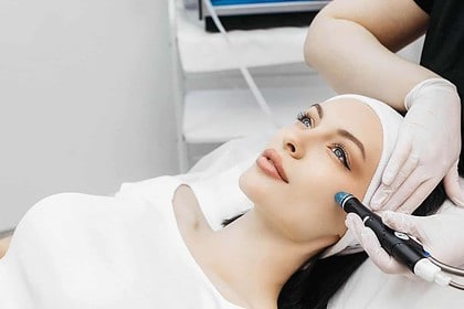 Woman receiving hydrafacial treatment at beauty clinic.